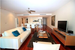 A modern living room with a white sofa, a coffee table, and a TV on a wooden stand.