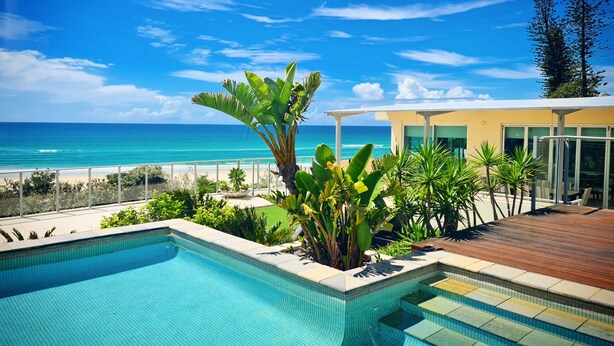 A pool with a view of the ocean, surrounded by tropical plants and a wooden deck. - The Beach Cabarita (Cabarita Beach)