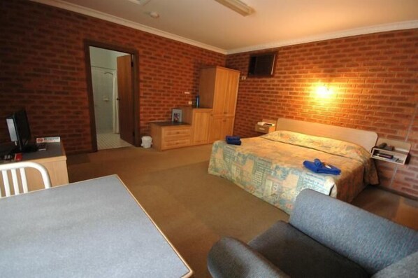 A room with a bed, a desk, a chair, a wardrobe, and a television.