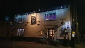 A building with a sign for 'The Dog's Head' pub, restaurant, and accommodation. There are hanging lights and a 'Car Park at Rear' sign. - The Nags Head (Norwich)