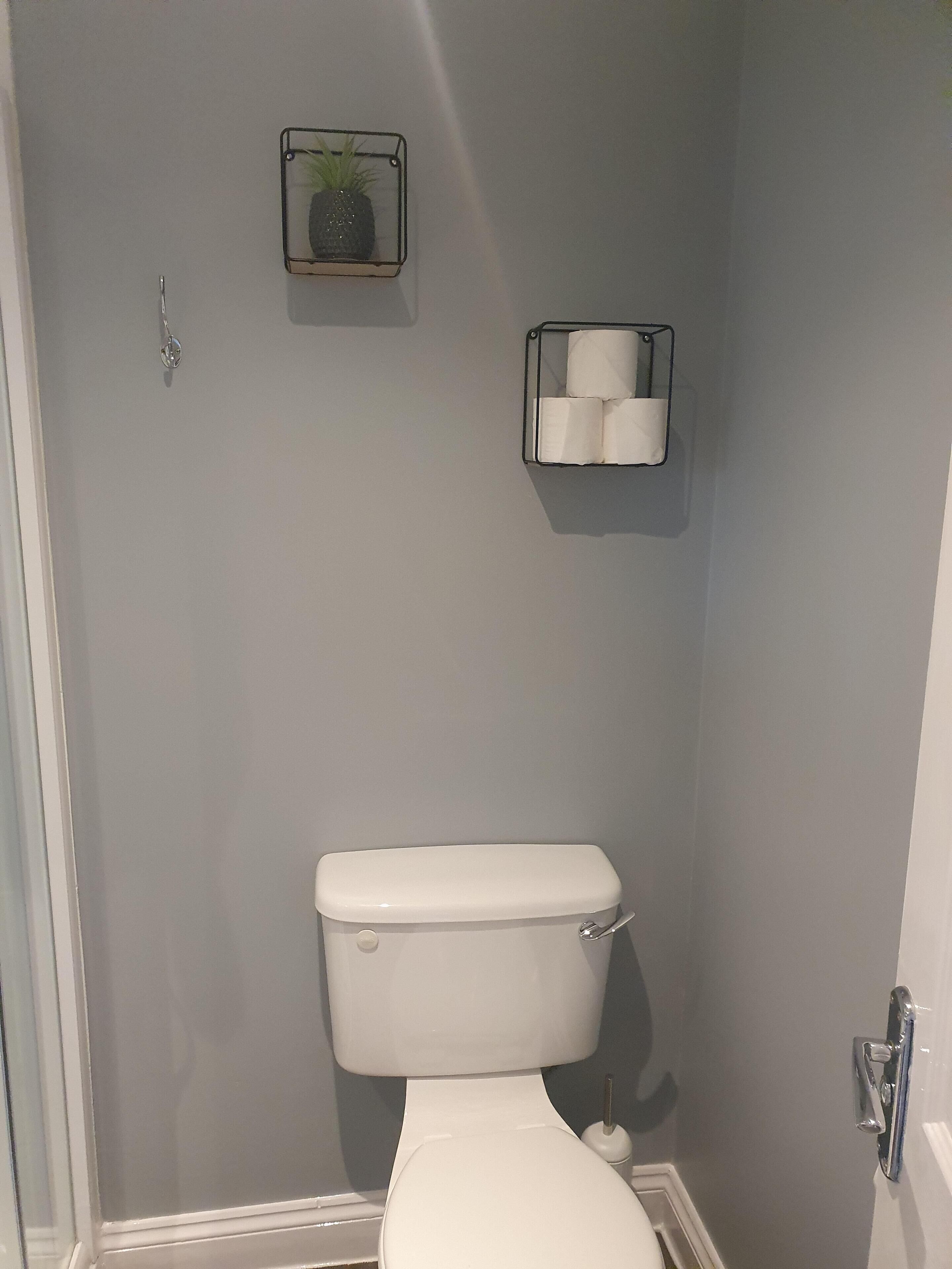 A bathroom with a toilet, a towel rack, and a toilet paper holder on the wall.