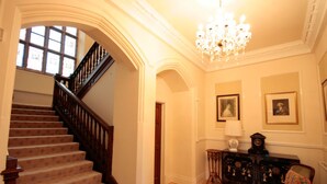 Un grand escalier menant à l’étage supérieur, un lustre et un mur orné de tableaux encadrés.