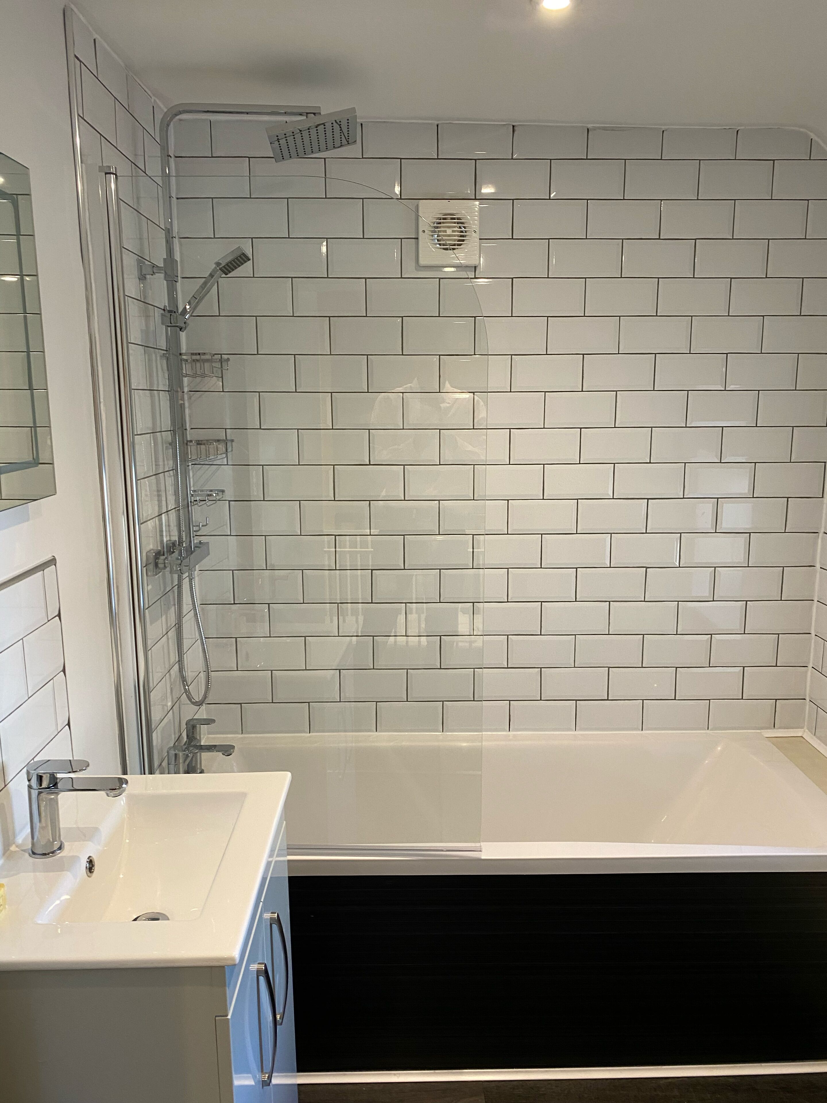 A modern bathroom with a glass-enclosed shower, a white sink, and a black cabinet.