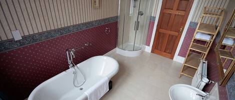 Un baño con una bañera independiente, ducha con cerramiento de vidrio, lavamanos y estante de madera.
