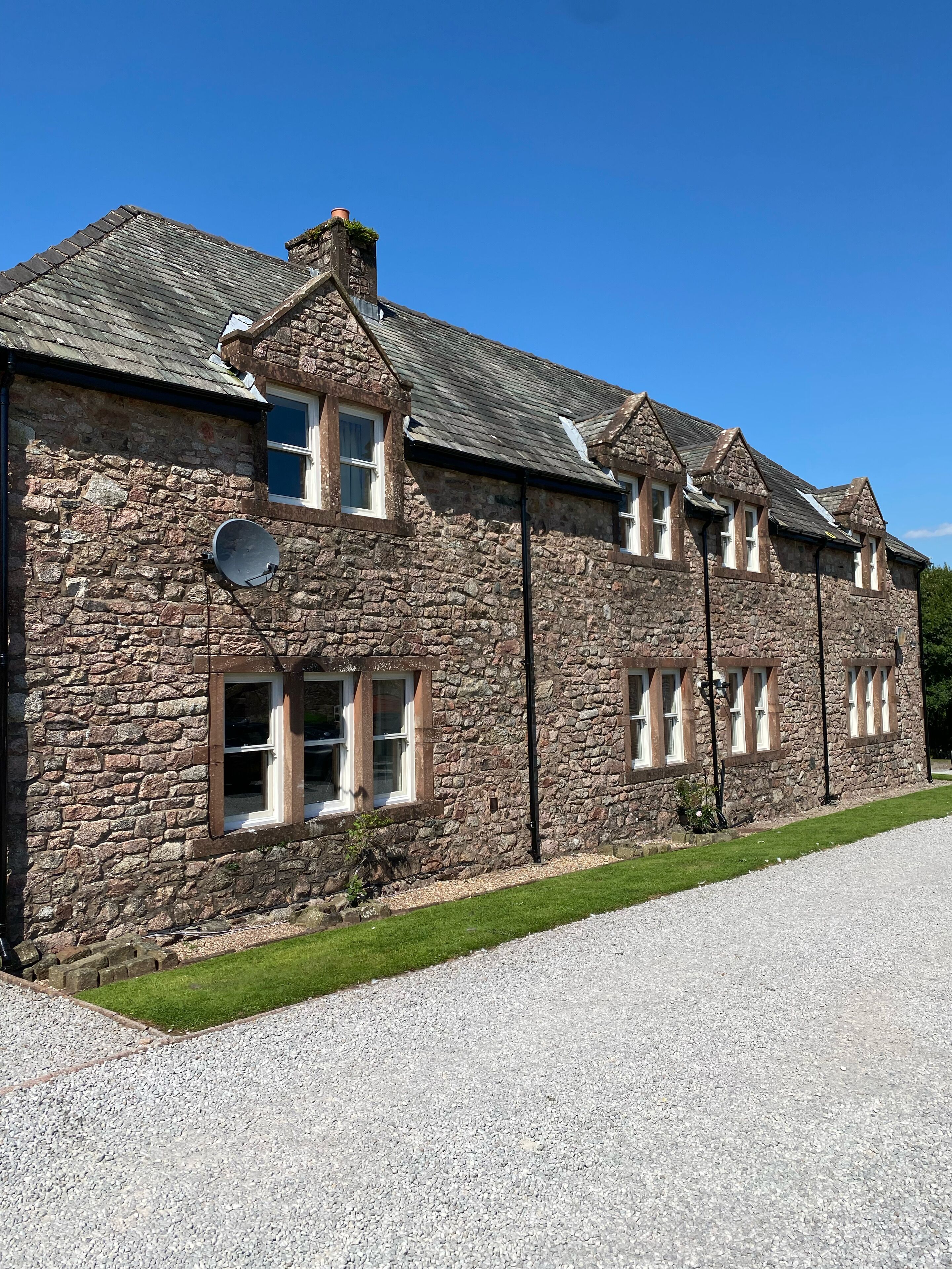 A stone building with multiple windows and a gravel driveway.