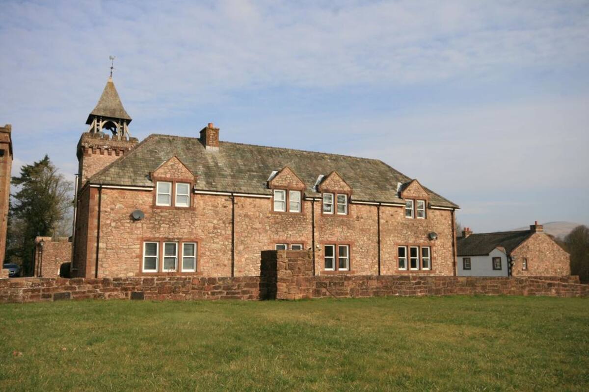 A stone building with a central tower and multiple windows.