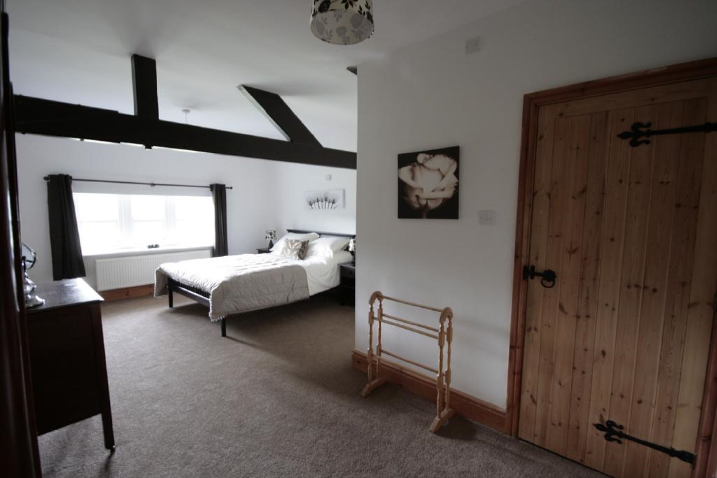 Une chambre à coucher avec un lit, une armoire en bois, un radiateur et une fenêtre avec des rideaux.