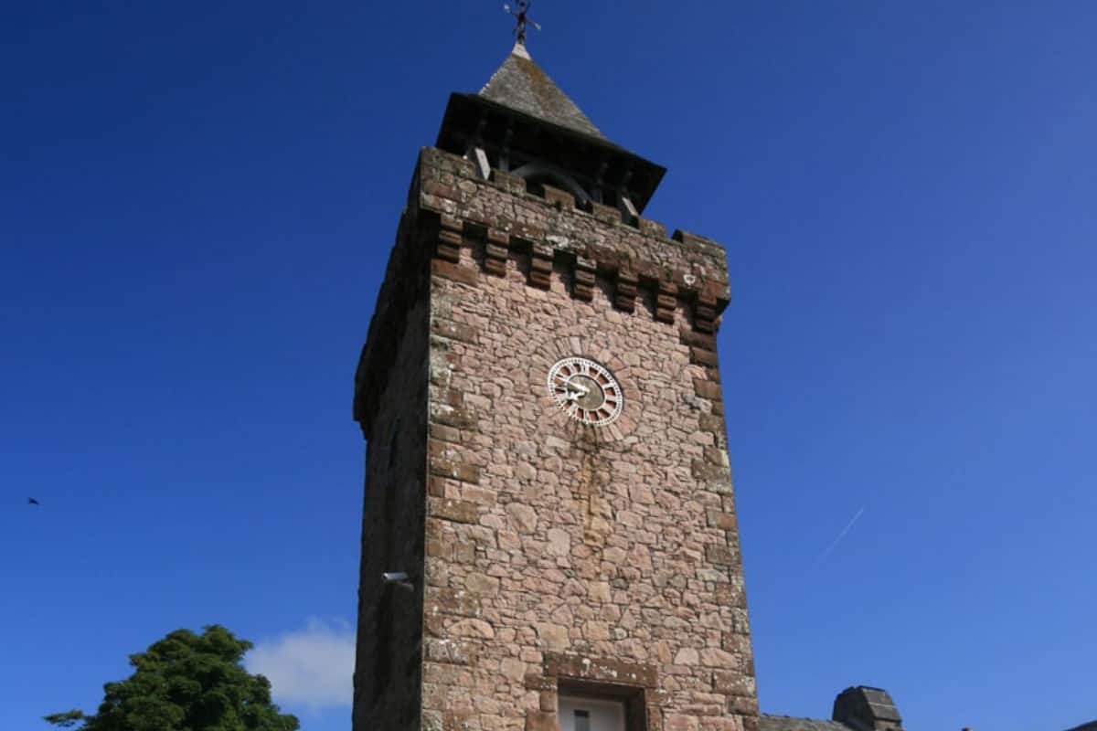 A stone tower with a clock, a door, and a small window.