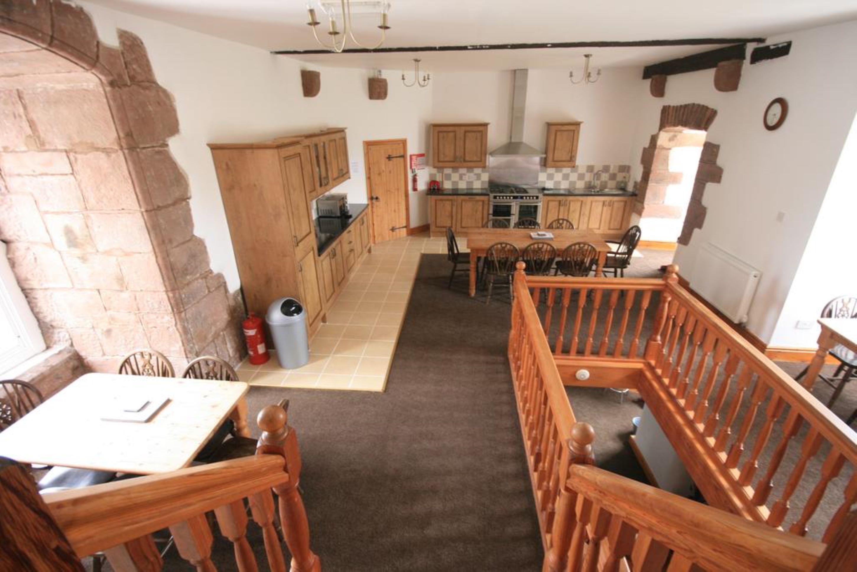 A rustic kitchen with wooden cabinets, a central island, and a dining area with wooden chairs and a table.