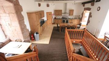 A rustic kitchen with wooden cabinets, a central island, and a dining area with wooden chairs and a table.