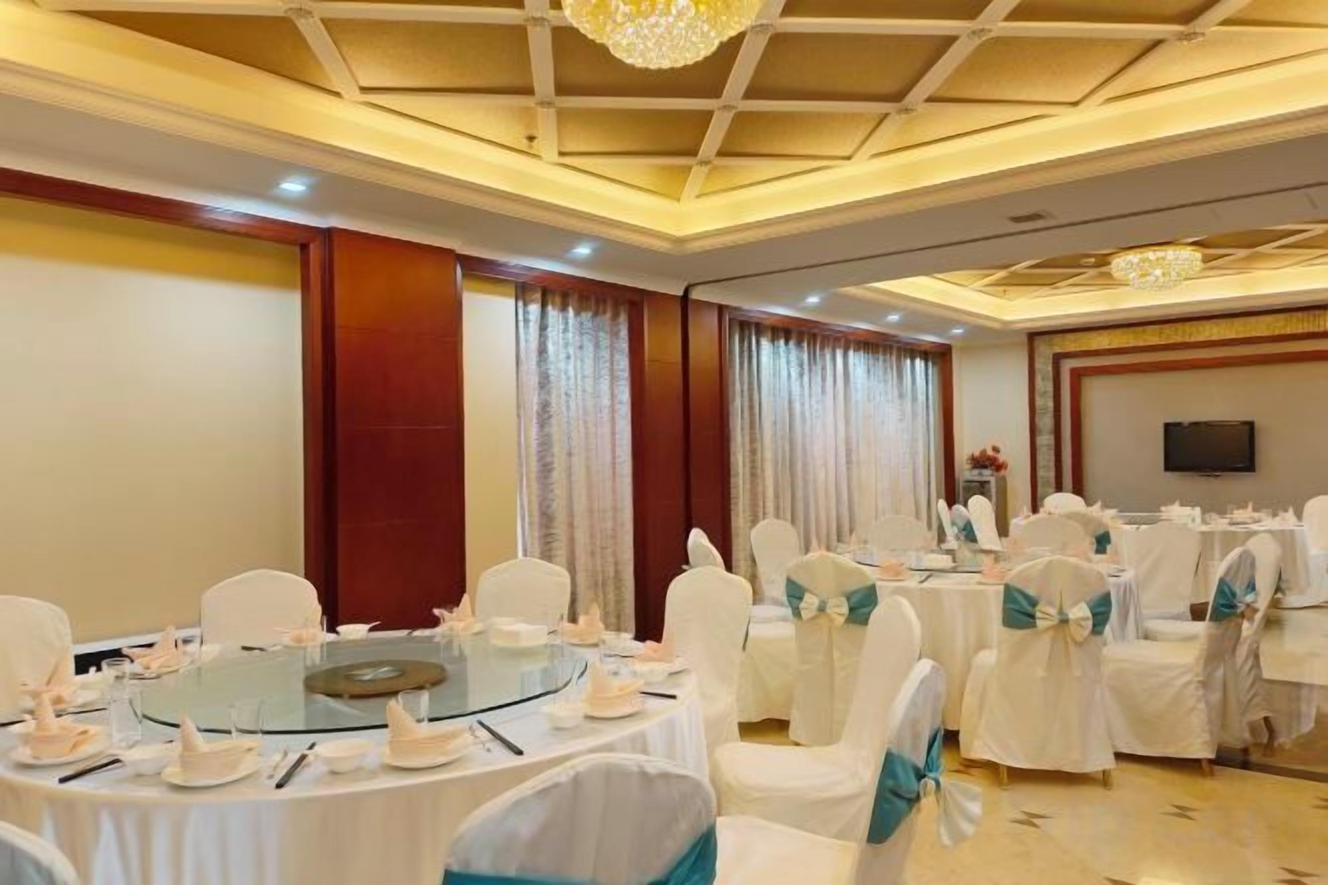 A conference room with round tables, white chairs, and a chandelier.