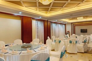 A conference room with round tables, white chairs, and a chandelier. - Silver Lake Island Hotel At Lugu Lake, Yunnan (Lijiang)