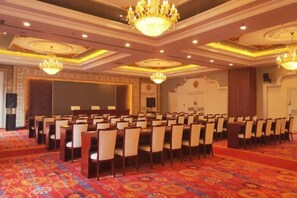 A conference room with rows of tables and chairs, a patterned carpet, and chandeliers. - Silver Lake Island Hotel At Lugu Lake, Yunnan (Lijiang)