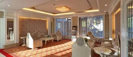 A spacious room with a red patterned carpet, a sofa set, a round table, and a decorative mirror.