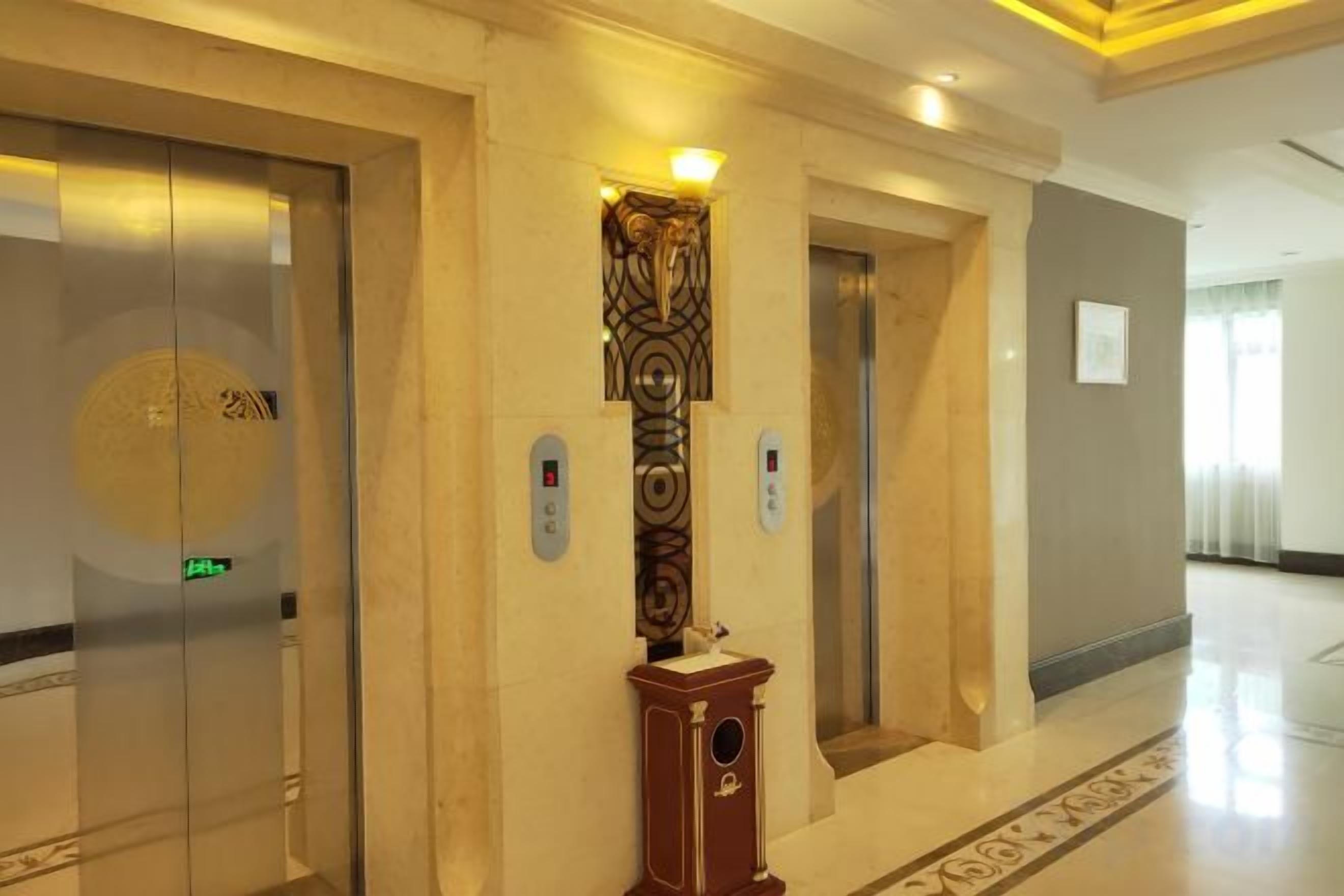Ένας διάδρομος με δύο ασανσέρ, ένα διακοσμητικό στοιχείο στον τοίχο και ένα δάπεδο με σχέδια.