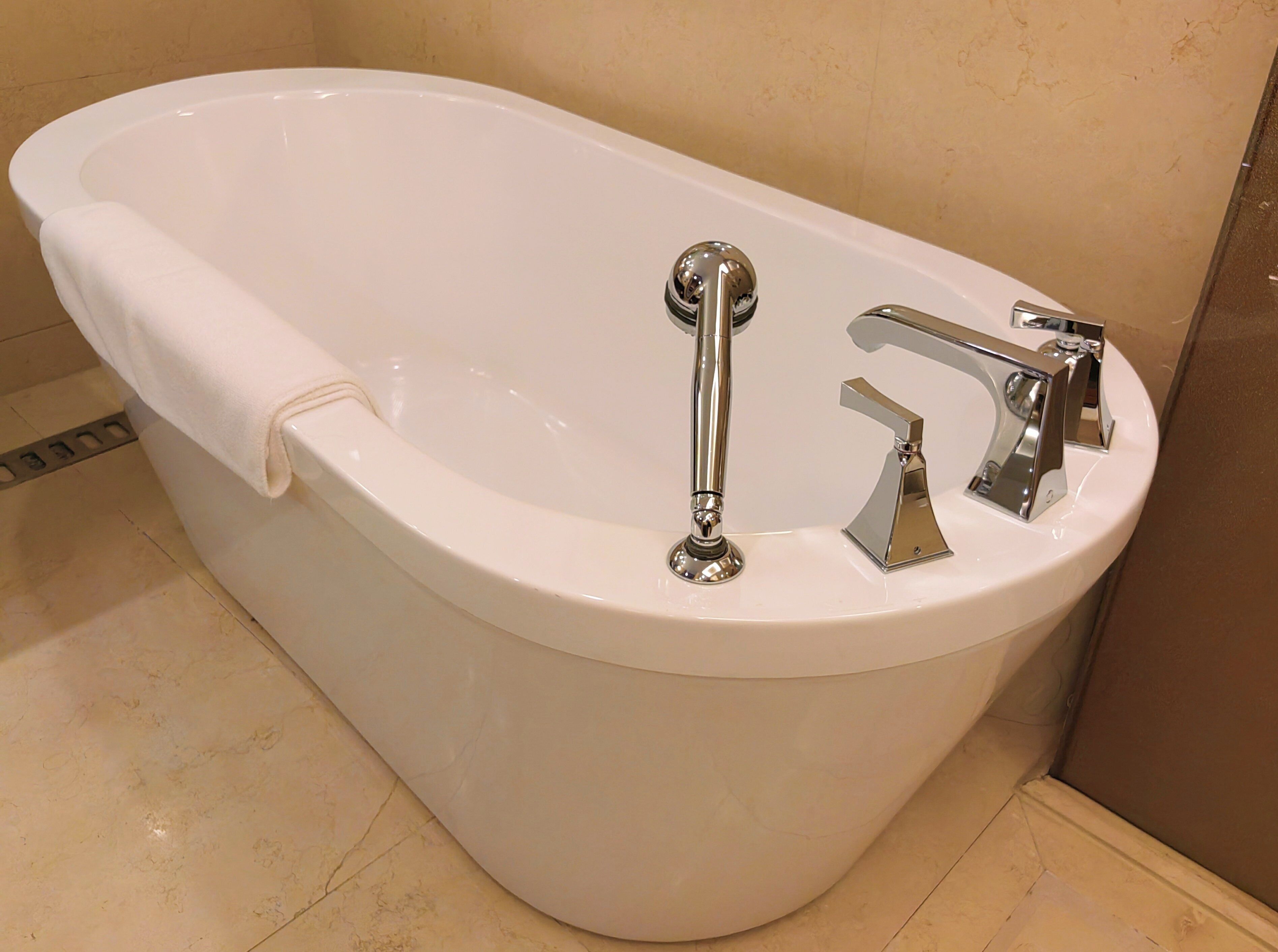 A white bathtub with a chrome faucet and a handheld showerhead.