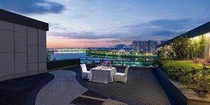 A rooftop terrace with a table set for dining, overlooking a cityscape and a river. - Crowne Plaza Huangshan Yucheng by IHG (Huangshan)