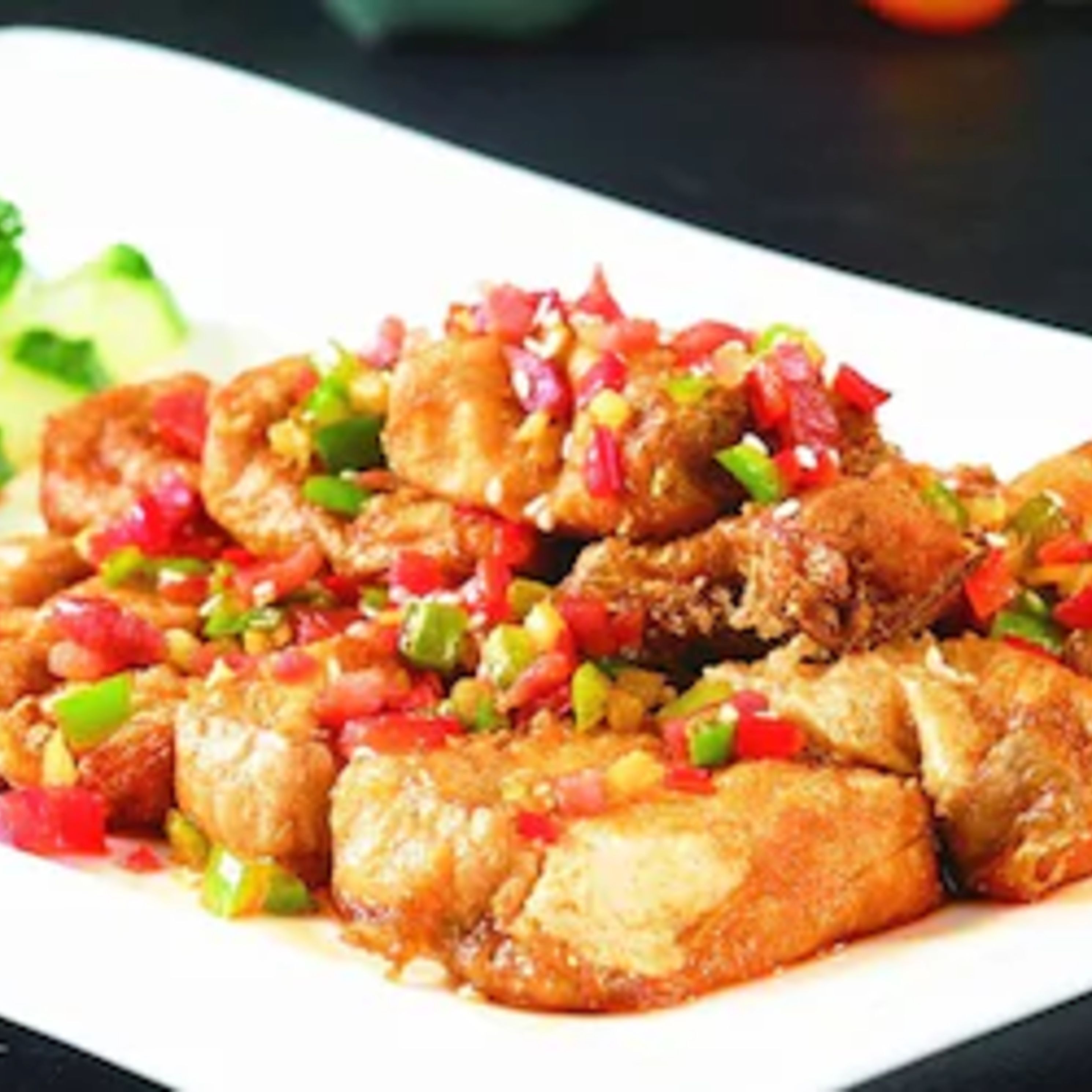A plate of fried chicken with diced bell peppers and onions.