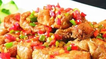 A plate of fried chicken with diced bell peppers and onions.