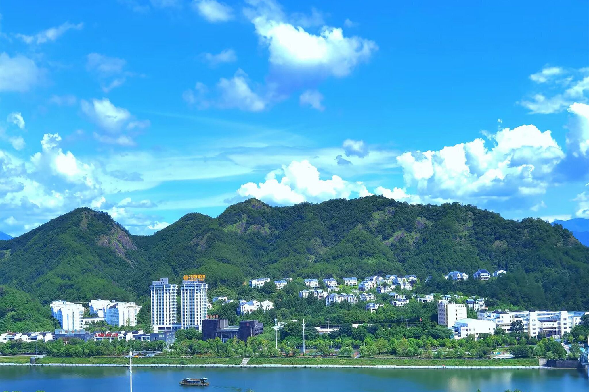 A coastal cityscape with a prominent hill, buildings, and a body of water.