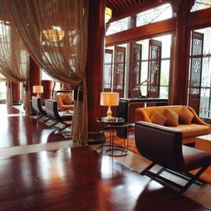 A spacious room with a wooden floor, a sofa, a chair, and a table with a lamp. - Crowne Plaza Huangshan Yucheng by IHG (Huangshan)