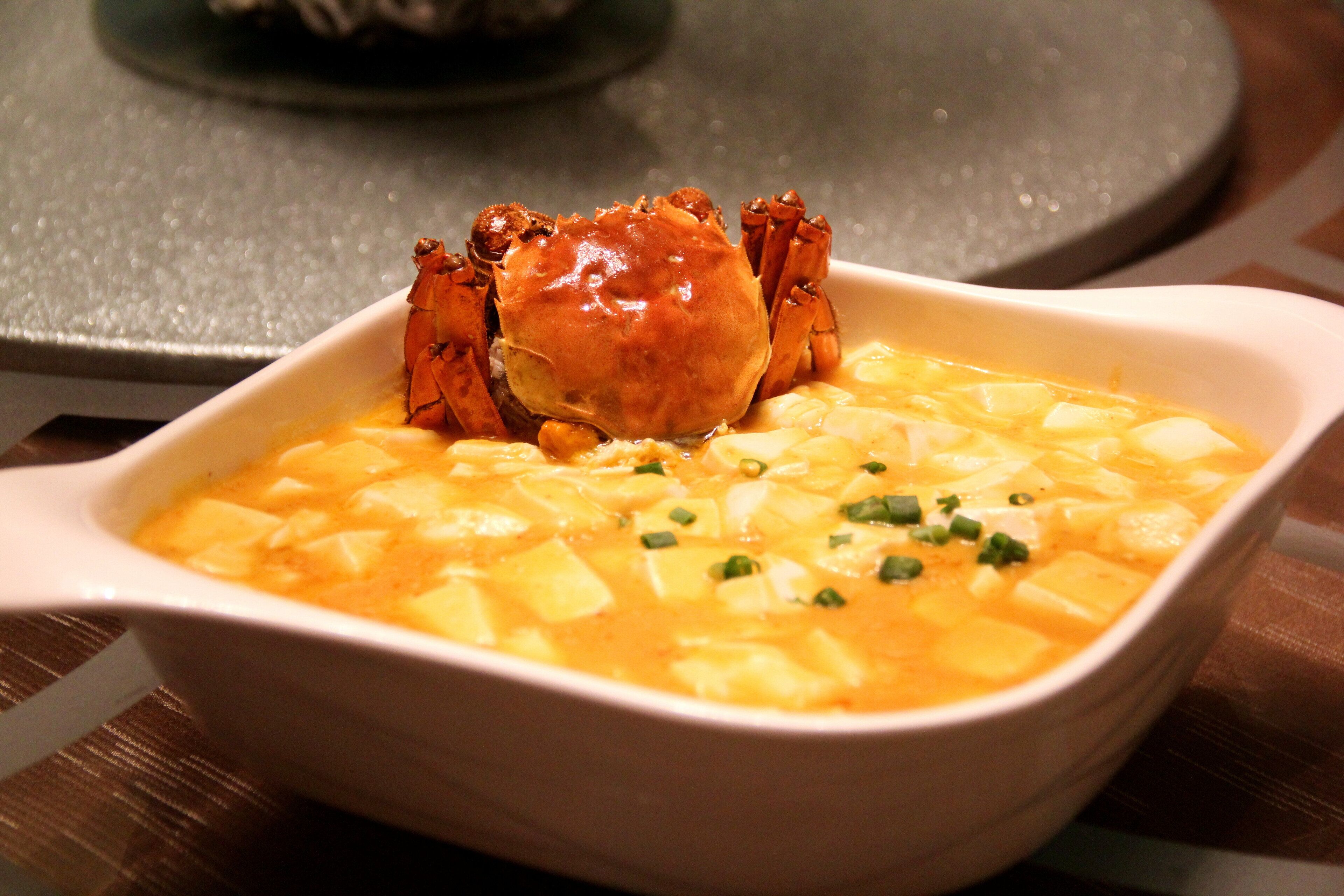 A bowl of soup with a crab on top.