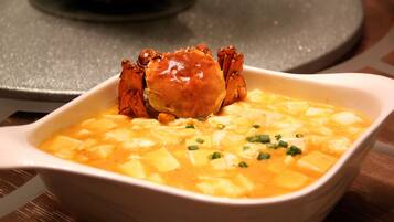 A bowl of soup with a crab on top.
