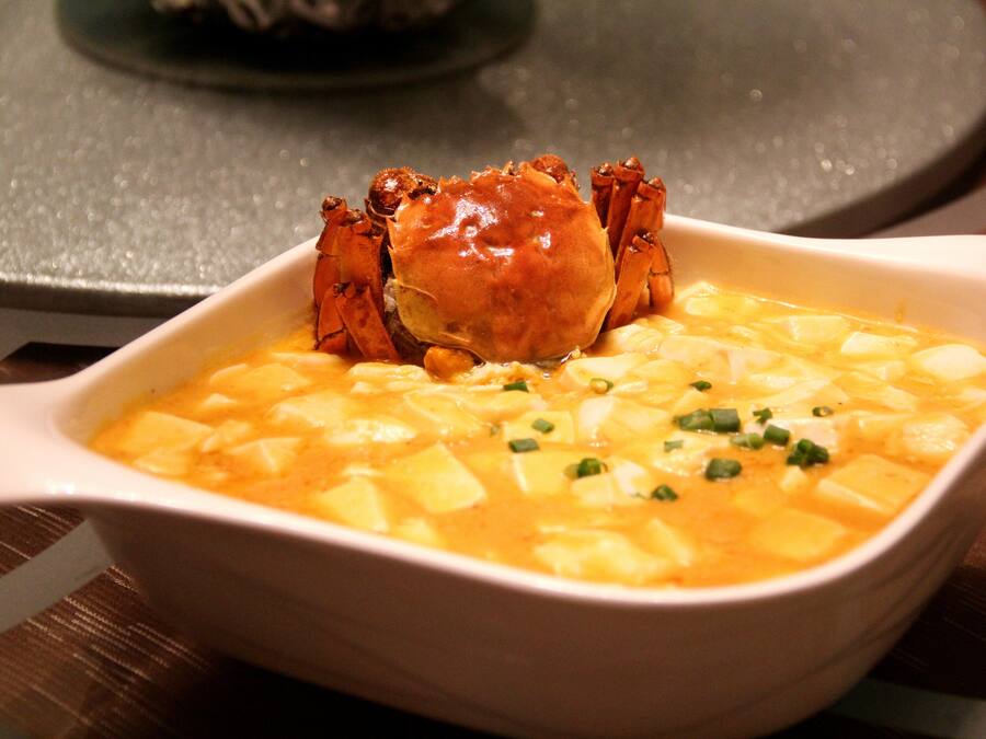 A bowl of soup with a crab on top.