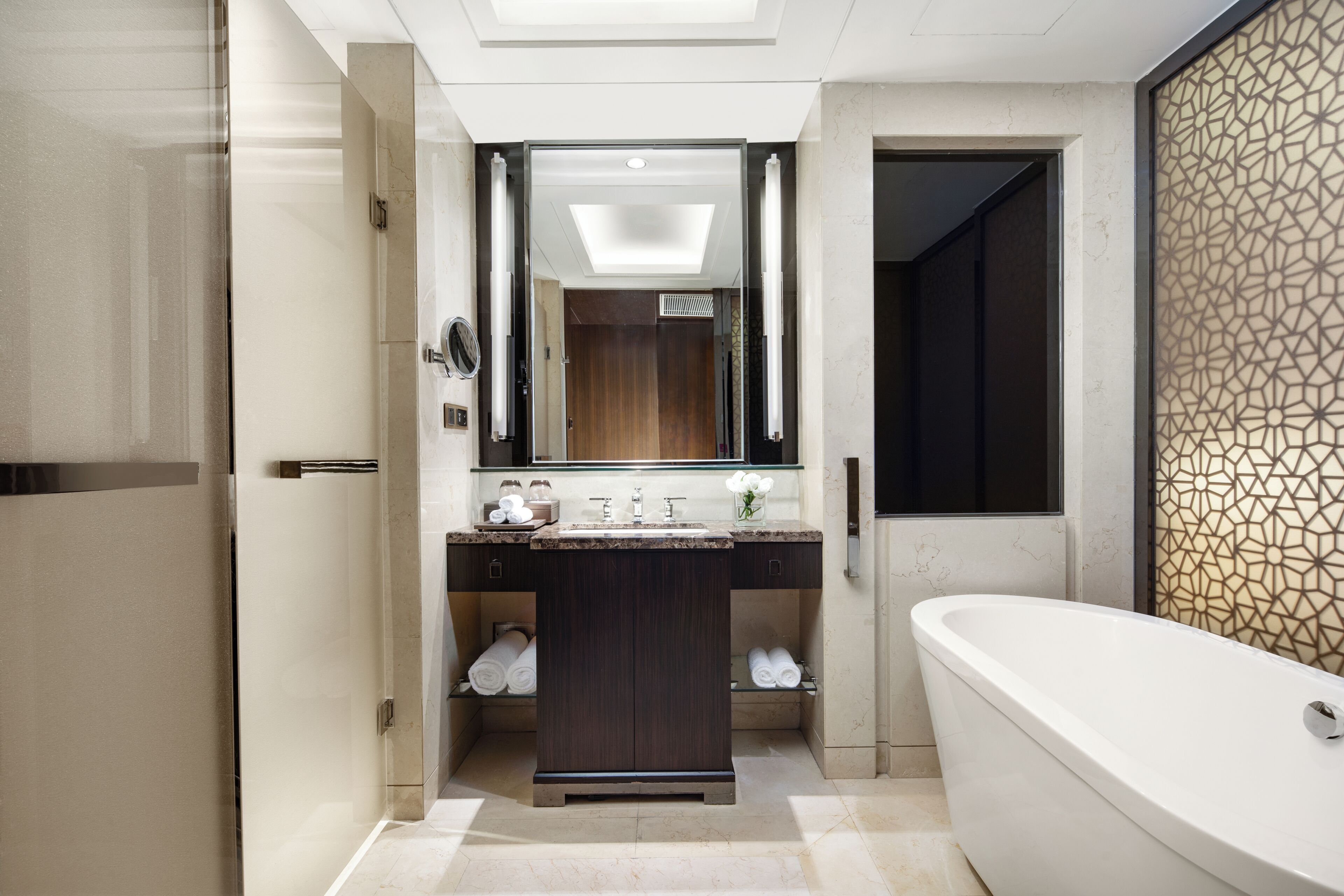 A modern bathroom with a freestanding bathtub, a glass shower enclosure, and a vanity with a mirror.