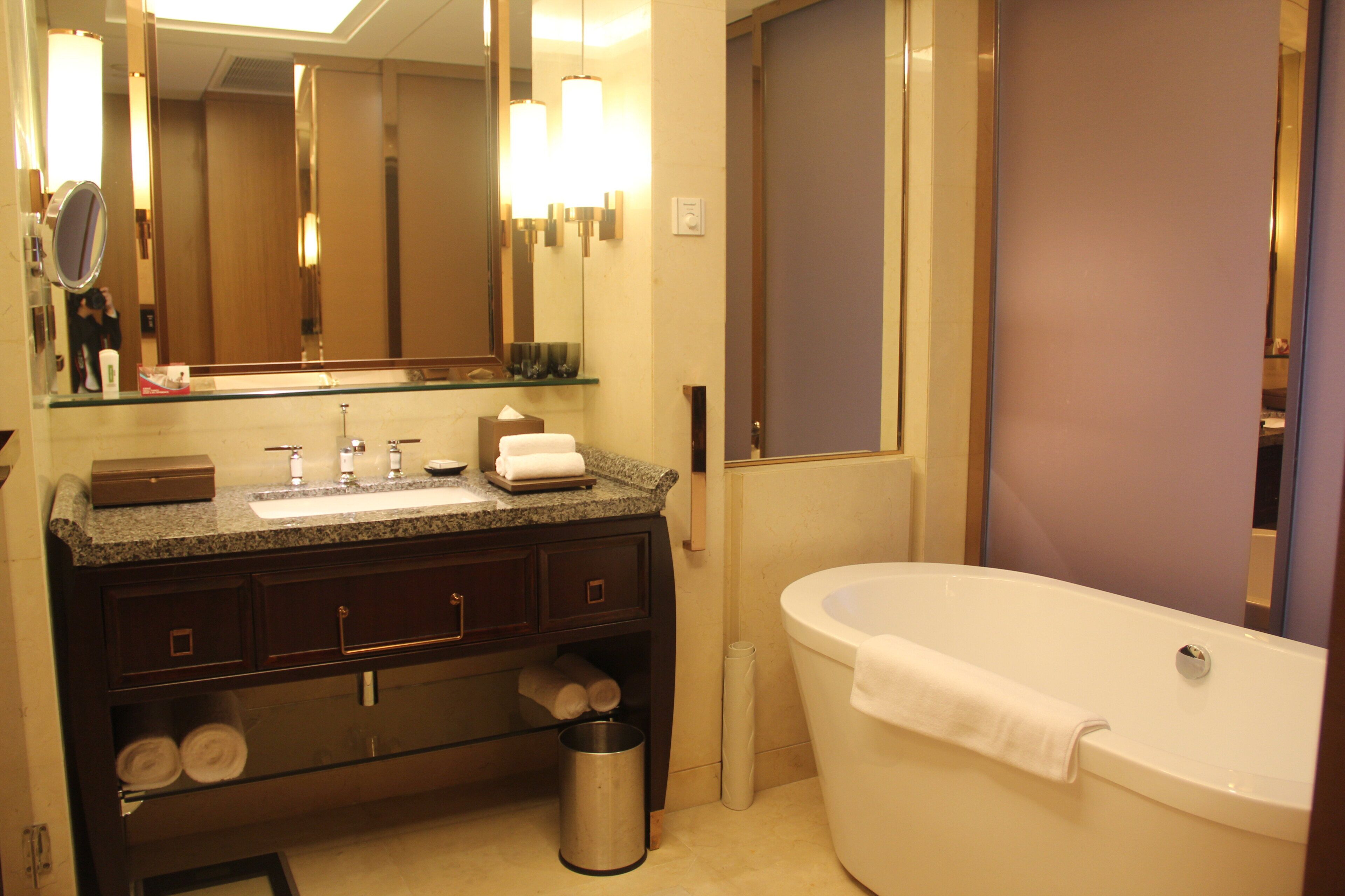 A bathroom with a sink, mirror, vanity, and a bathtub.