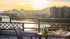 Un balcon offrant une vue sur le paysage urbain et la rivière au coucher du soleil.