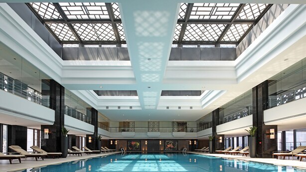 Una amplia piscina cubierta con varios niveles de balcones y zonas de descanso.