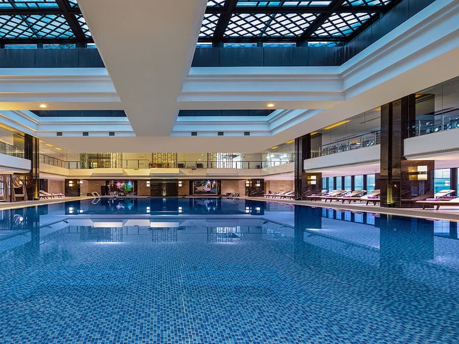 A large indoor swimming pool with multiple levels of balconies and lounge areas.