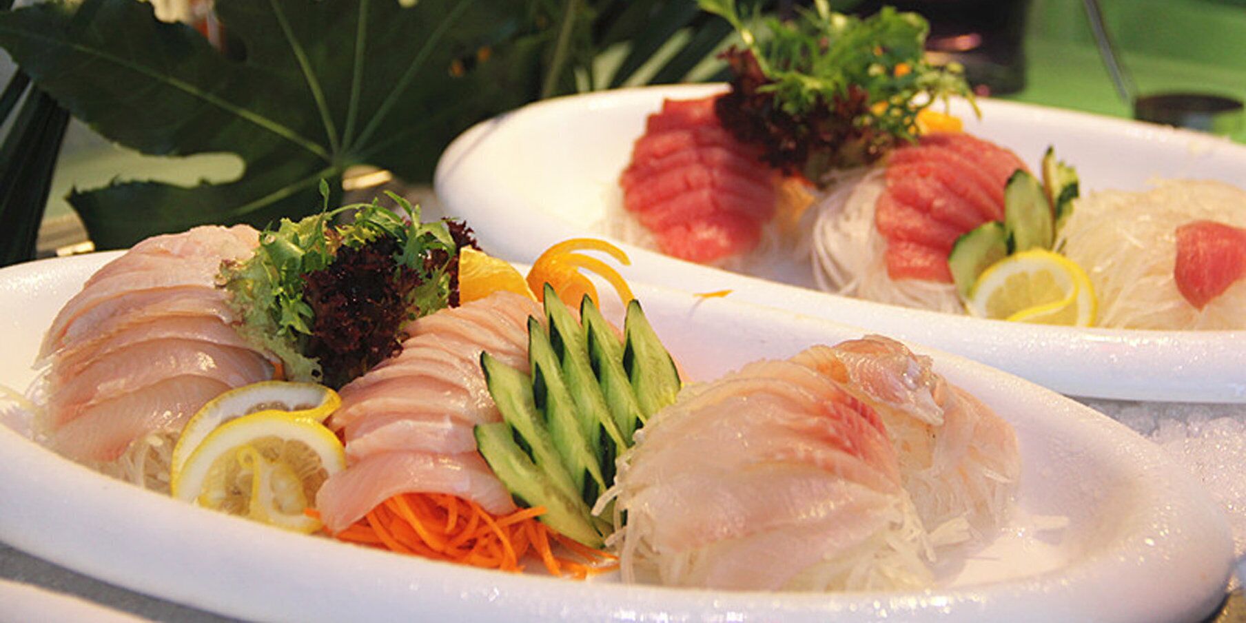 Diverse sashimi gerechten op borden, voorzien van garnering.