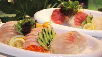 Diverse sashimi gerechten op borden, voorzien van garnering.