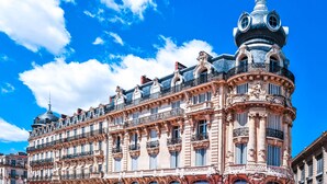 Un edificio histórico con detalles arquitectónicos ornamentales, incluyendo una cúpula destacada y varios balcones.