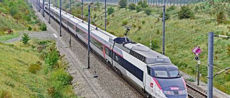 A high-speed train traveling on a railway track surrounded by greenery.