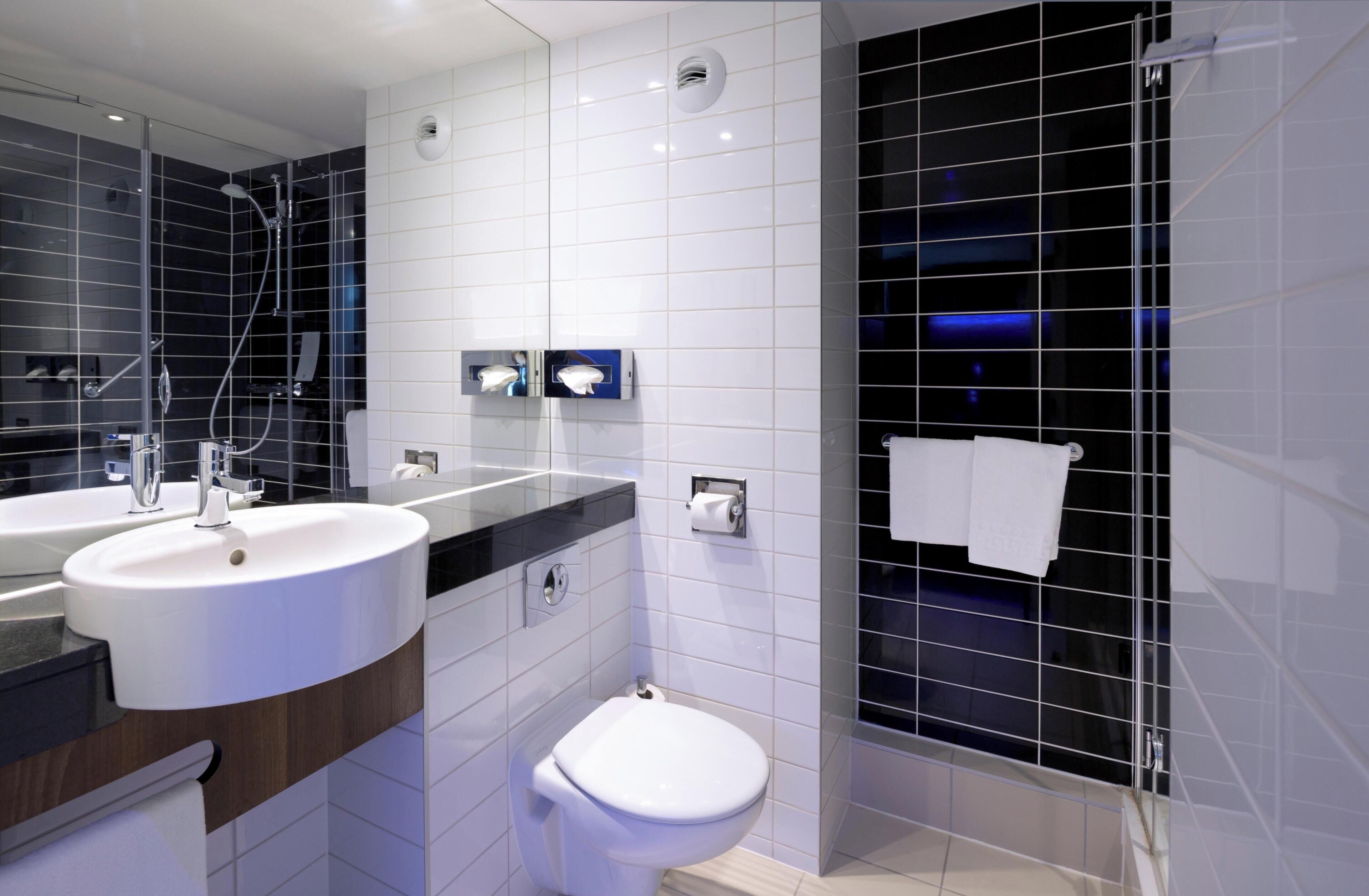 Une salle de bain moderne avec un double lavabo, des toilettes et un espace douche.