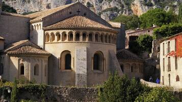 A historic building with a central dome and arched windows, surrounded by stone walls and vegetation.