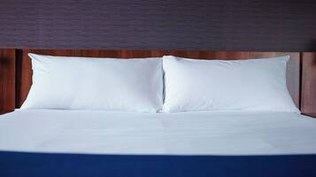 Uma cama com roupa de cama branca e cabeceira de madeira.