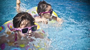 Dos personas en una piscina con flotadores.