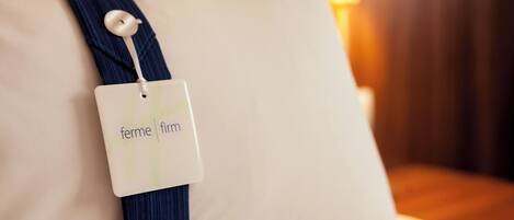 A pillow with a tag labeled 'ferme firm' attached to it.