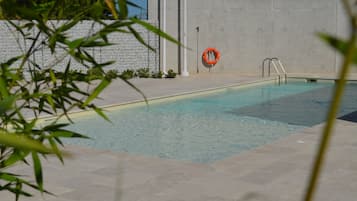 Une piscine équipée d’une bouée de sauvetage et d’une échelle métallique.