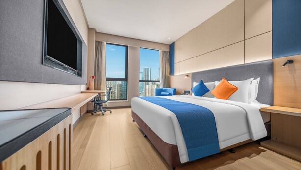 Une chambre d’hôtel moderne avec un grand lit, un bureau et une télévision.