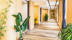 Un couloir d’hôtel avec un plancher en bois, des plantes en pot et un design moderne.
