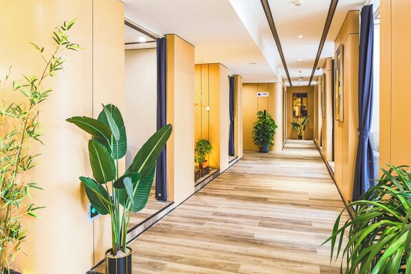 Ein Hotelgang mit Holzboden, Blumentöpfen und modernem Design.