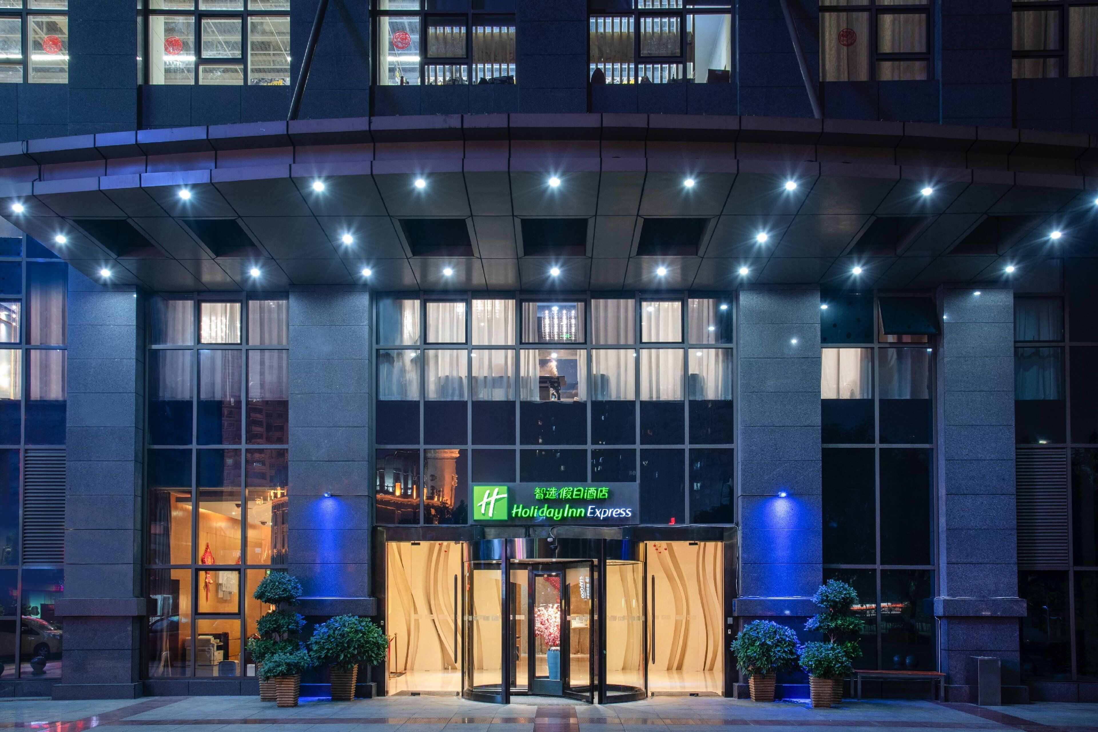 A hotel entrance with a glass facade, a revolving door, and a sign for Holiday Inn Express.