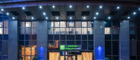 A hotel entrance with a glass facade, a revolving door, and a sign for Holiday Inn Express.