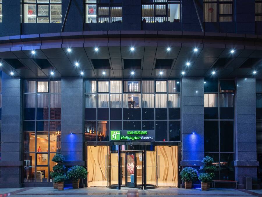 Ingresso di un hotel con facciata in vetro, una porta girevole e il cartello Holiday Inn Express.