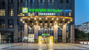 L’entrée d’un hôtel Holiday Inn Express, caractérisée par un design moderne, de grandes fenêtres et une façade bien éclairée.